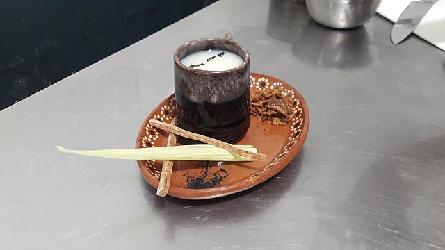 a cup of atole in a ceramic cup on a decorative ceramic plate
