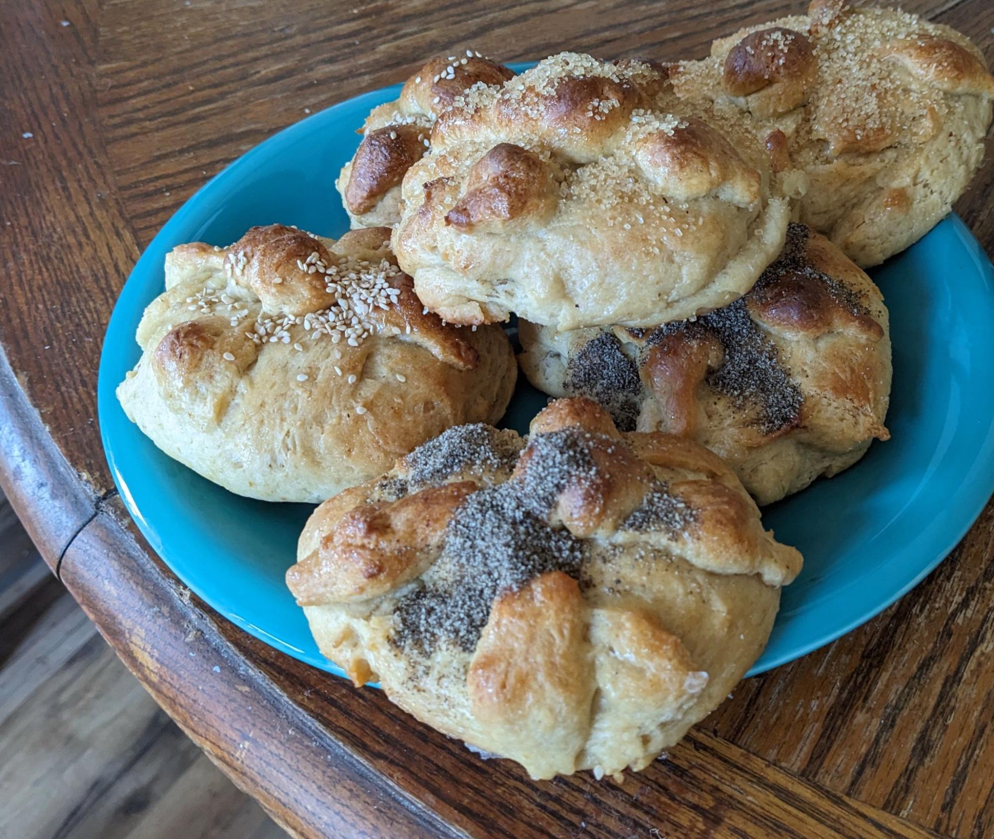 Small bread loaves with two bone shaped bread strips on top,
     covered either with sesame seeds or chia seeds